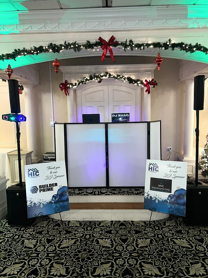 Holiday-themed DJ setup beneath seasonal garland and ornaments with event signage.